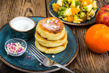 Hot delicious curd pancakes with fruit salad and yogurt