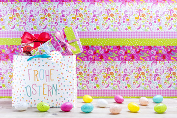 Ostergeschenke und bunte Ostereier vor einem bunten Hintergrund