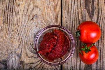 Tomato paste, ketchup, cherry tomatoes on wooden table