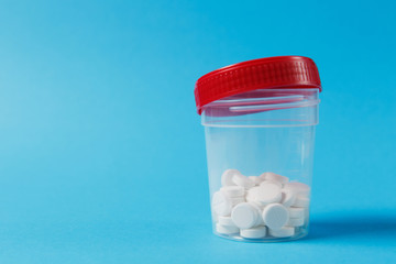 Medication jar with white round tablets arranged abstract on blue color background. Aspirin bottle...
