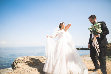 Happy and romantic scene of just married young wedding couple posing on beautiful beach