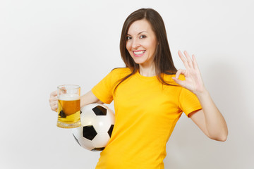 Beautiful European young cheerful woman, football fan or player in yellow uniform holding pint mug of beer, soccer ball isolated on white background. Sport, play football, healthy lifestyle concept.