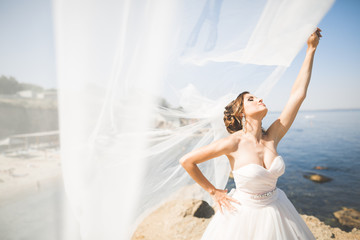 Beautiful young bride with bridal bouquet posing on the background sea