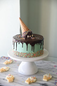 Cake with melted ice cream decoration, on cake stand, with ice cream cookies