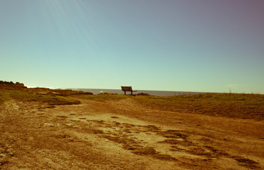 Single bench on a clifftop with a blue sky