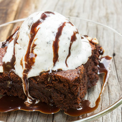 Homemade brownies with ice cream on top and chocolate sauce are topping.