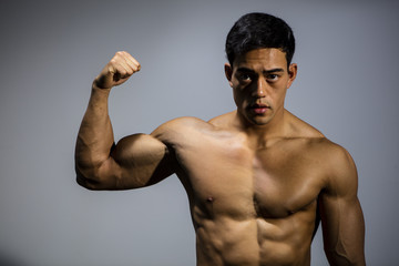 Fototapeta na wymiar Asian Fitness Model Flexes Bicep Muscle