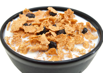 bran and raisin cereal in a bowl and milk on white