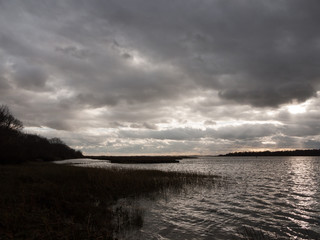 Fototapeta premium moody sky clouds autumn winter grey dark bay ocean river estuary