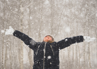Little girl with arms wide open in snow weather. - obrazy, fototapety, plakaty