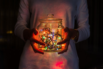 Girl hands holding mason jar with fairy lights
