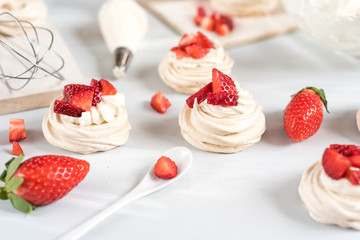 Strawberry pavlova cake nests, meringue decoration on a culinary table