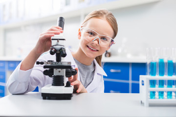 Little happy girl studying microscope functions