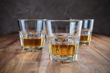 three glasses of whiskey on the oak surface of the table