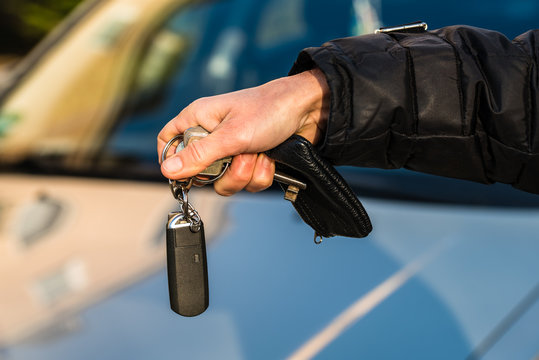 Hand mit Autoschl&uuml;ssel Schl&uuml;sselbund und Auto