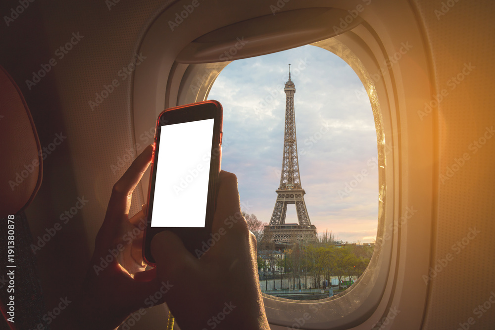 Poster woman sitting by aircraft window and using a digital mobile during the flight. eiffel tower as seen 