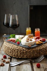 Red wine and a variety of snacks. Rustic wooden table and dark gray background
