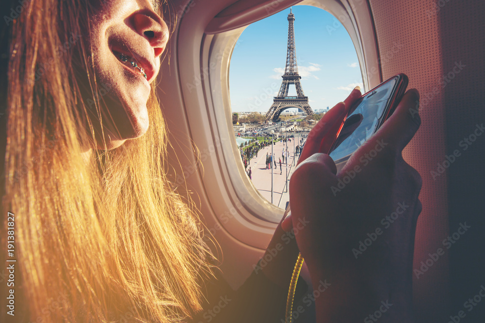 Poster woman sitting by aircraft window and using a digital mobile during the flight. eiffel tower as seen 