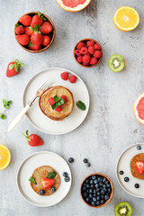 Breakfast table with pancakes, berries and fruits. Top view, gray light background
