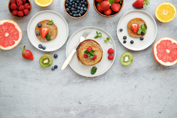 Fototapeta na wymiar Breakfast table with pancakes, berries and fruits. Top view, gray light background 