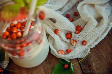 Homemade strawberry yogurt with fresh wild strawberries and mint in a jar on a wooden board, selective focus