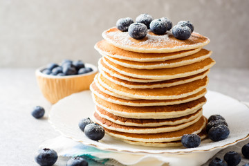 Pancakes with blueberries and sugar on grey stone background.