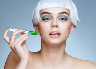 Beautiful woman face with syringe makes cosmetic injection in the lips. Clean Beauty concept