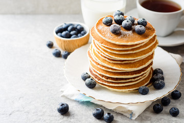 Pancakes with blueberries and sugar on grey stone background.