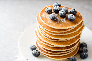 Pancakes with blueberries and sugar on grey stone background.