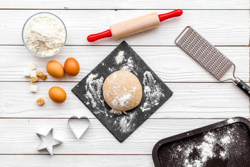 Roll out the dough. Dough ball near roller pin and other cookware on white wooden background top view