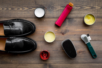 Fototapeta na wymiar Shoe care products. Leather men shoes, shoe polish, brushes, wax on dark wooden background top view