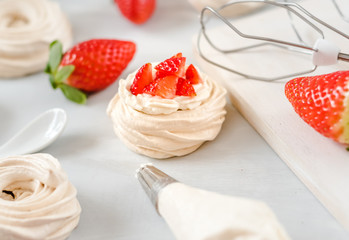 Strawberry pavlova cake nests, meringue decoration on a culinary table