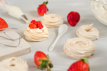 Strawberry pavlova cake nests, meringue decoration on a culinary table
