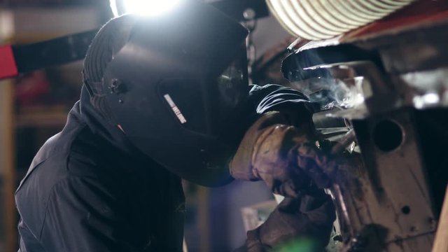 Male worker at a welding factory in a protective eyewear. Welding on an industrial plant. Slow motion.