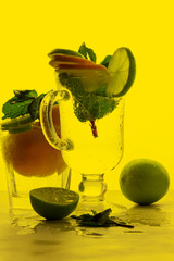 Mojito with lime and lemon and mint, cocktail with ice in a glass cup, soft drink with ice on a light background, empty space, cocktail pop art, toned background, summer drink