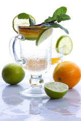 Mojito with lime and lemon and mint, cocktail with ice in a glass cup, soft drink with ice on a light background, empty space, cocktail pop art, toned background, summer drink