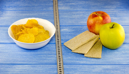 Chips apples breads centimeter tape on a blue wooden background
