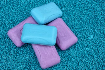 куча из  мыла красного и синего цвета на мелком зелёном песке