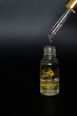 Luxurious facial serum container with dropper on black background