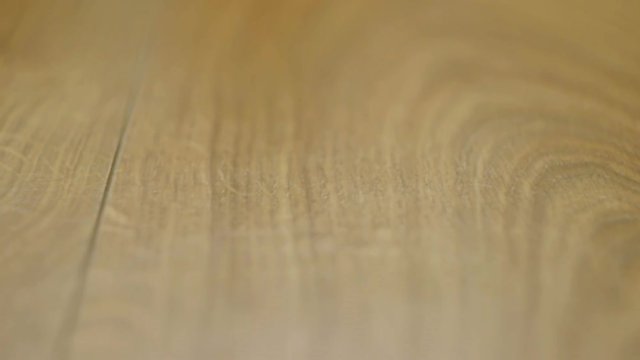 The camera moves along the floor, covered with laminated parquet with a brown wooden texture