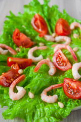 Salad of peeled shrimps and cherry tomatoes served on a leaf of fresh lettuce. Mediterranean Kitchen. Serving option. Close-up