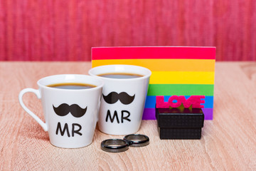 Gay marriage concept. Two cups of coffee, gay flag and a black gift box with marriage ring