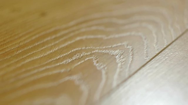 The camera moves along the floor, covered with laminated parquet with a brown wooden texture