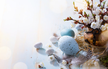 Happy Easter;  Easter eggs and sprig flowers on blue table background