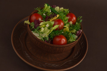 Fresh salad with iceberg, arugula, cherry tomatoes, chinese and red cabbage in clay dish