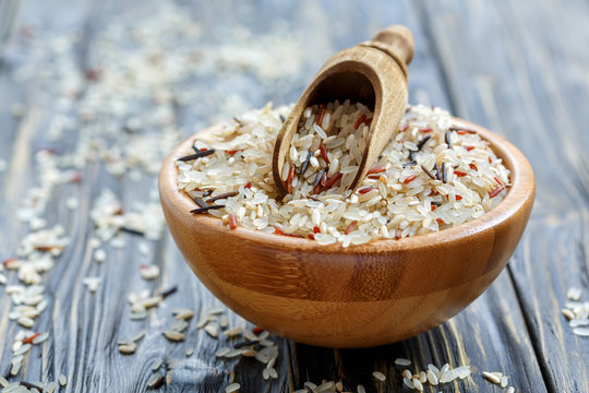 Wooden scoop in a bowl with a mixture of four types of rice.