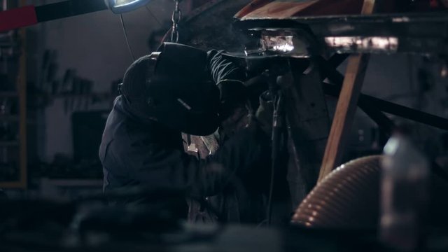 Welder working on bottom side of the car at a mechanical hangar.