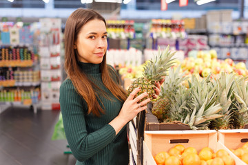 Young brunette woman buying pineapple