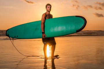 Surfer with surfboard on the beach