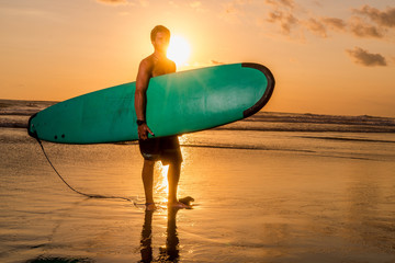 Surfer with surfboard on the beach